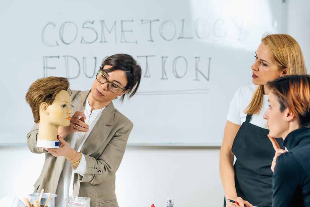 A Rizzieri Salon and Spa educator teaches high school students with a hair model